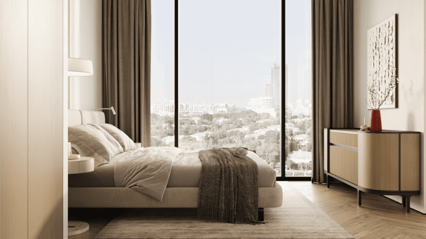 Chambre moderne à Arisha Terraces avec une grande baie vitrée offrant une vue imprenable sur la ville. La chambre comprend un lit confortable, une table de chevet avec lampe et une commode avec un vase décoratif. Les tons neutres et la décoration minimaliste créent une atmosphère sereine.