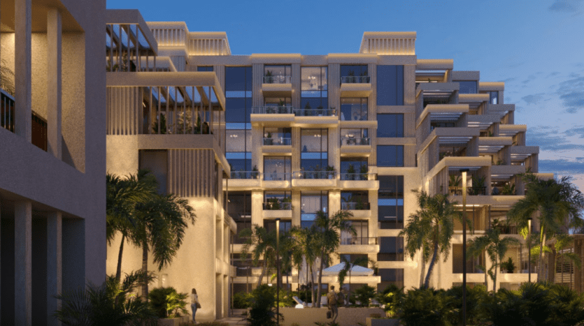 L'immeuble moderne à plusieurs étages d'Arisha dispose de grandes baies vitrées et de terrasses. Entouré de palmiers et d'une végétation luxuriante au crépuscule, il dégage une atmosphère accueillante avec son éclairage chaleureux.