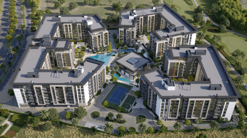 Vue aérienne d'un complexe résidentiel composé de six bâtiments à plusieurs étages disposés autour d'une cour centrale. La cour comprend une piscine, des jardins paysagers et un court de tennis. Les environs sont luxuriants avec des arbres et de la verdure.