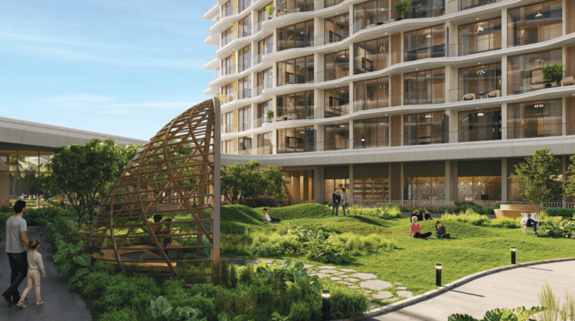Une cour urbaine moderne avec un bâtiment à plusieurs étages avec balcons et espaces verts. Les gens se détendent sur l'herbe et se promènent. Une structure en bois en forme de dôme se trouve au premier plan, avec un jardin paysager et un ciel dégagé.