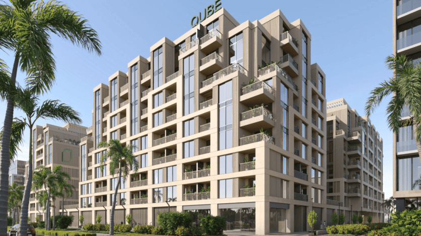Le QUBE, un immeuble d'appartements moderne doté de grandes fenêtres et de balcons, est entouré de la beauté luxuriante des terrasses d'Arisha. Entouré de palmiers et de verdure paysagée sous un ciel bleu clair, il offre une oasis de tranquillité au cœur de la ville.