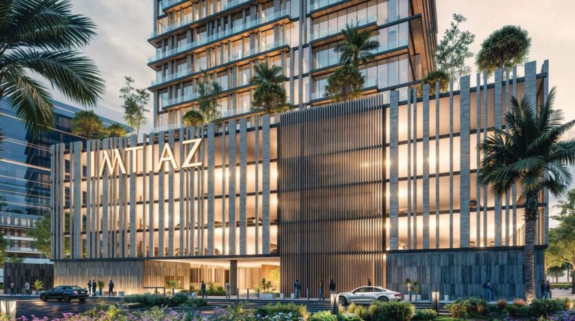 Un immeuble moderne de plusieurs étages, avec de grandes baies vitrées et des lames métalliques verticales sur sa façade, se dresse fièrement le long du boulevard Cove. Le bâtiment, baptisé « IMTIAZ », arbore des terrasses verdoyantes. Au premier plan, des palmiers se balancent doucement à côté d'une voiture garée.