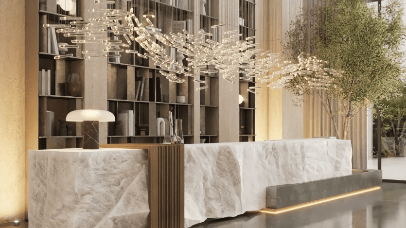 Un intérieur moderne sur Cove Boulevard présente un grand bureau en pierre texturé avec une lampe élégante. Au-dessus, des luminaires en verre complexes créent une présentation élégante. En arrière-plan, une grande bibliothèque et un grand arbre d'intérieur renforcent l'ambiance sophistiquée.