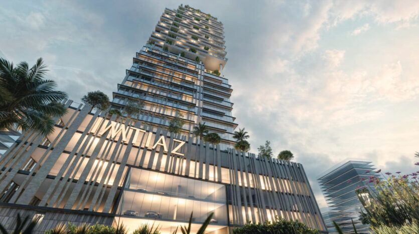 Un gratte-ciel moderne et haut de gamme, à plusieurs niveaux, se dresse fièrement sur Cove Boulevard, enveloppé de verdure sous un ciel nuageux. De grandes fenêtres reflètent l'environnement, tandis que « IWLAZ » marque son entrée. Au premier plan, des palmiers et des fleurs aux couleurs vives créent une oasis accueillante.
