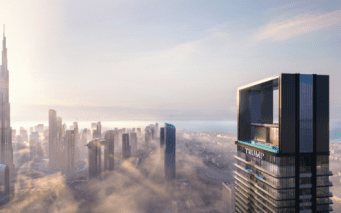 Une silhouette urbaine moderne au lever du soleil, avec de hauts gratte-ciels s'élevant au-dessus des nuages bas. La Burj Khalifa est visible à gauche, et un bâtiment portant l'inscription « TRUMP » est bien visible à droite.