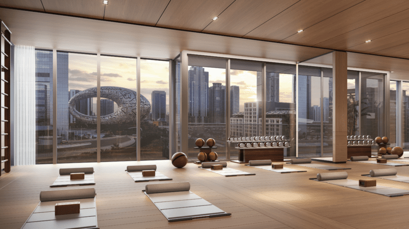 A modern yoga studio with carefully arranged mats, bolsters and yoga blocks, featuring picture windows overlooking the city's rooftops and Dubai's Museum of the Future at sunset.