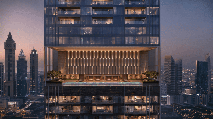 A modern high-rise building features a rooftop infinity pool with lounge seating and greenery, overlooking the city's rooftops at dusk with illuminated skyscrapers in the background.