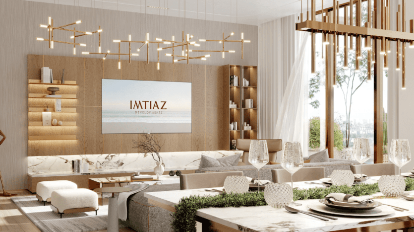 Salon et salle à manger modernes et élégants avec des tons neutres, de grandes fenêtres, des surfaces en marbre, des lustres contemporains et une télévision murale affichant « IMTIAZ » - le cadre idéal pour profiter du luxe inspiré de l'île de Wynnwood Dubai.