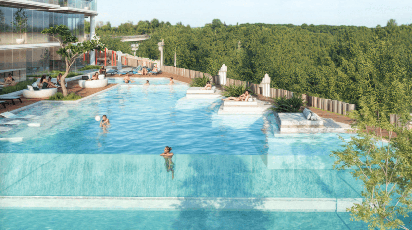 Une piscine à débordement moderne sur le toit avec des gens qui nagent et se prélassent, bordée de verdure et de transats, avec une vue panoramique sur la forêt en arrière-plan.