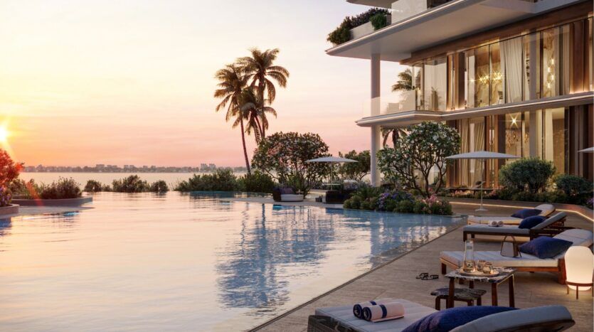Une piscine luxueuse au coucher du soleil sur les îles Silena de Dubaï, avec des chaises longues, des parasols, des plantes tropicales luxuriantes et un bâtiment moderne surplombant l'eau calme et l'horizon lointain de la ville.