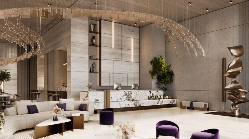 Le hall d'entrée moderne de la Résidence Le Blanc à Dubailand présente un bureau de réception en marbre, des lampes suspendues artistiques, des sièges violets, des canapés beiges, des sculptures abstraites et un décor en bois clair et en pierre. Des plantes vertes ajoutent une touche de nature à cet espace élégant.