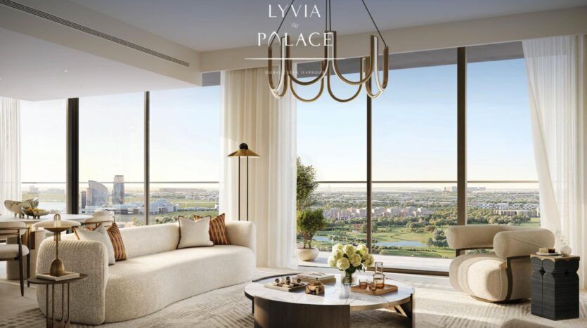 Le salon moderne et élégant de la Résidence Lyvia by Palace à Dubai Creek Harbour se caractérise par un mobilier de couleur crème, de grandes fenêtres allant du sol au plafond et offrant une vue sur la ville et les paysages verdoyants, une table basse ronde ornée de fleurs et un lustre contemporain au-dessus de la tête.