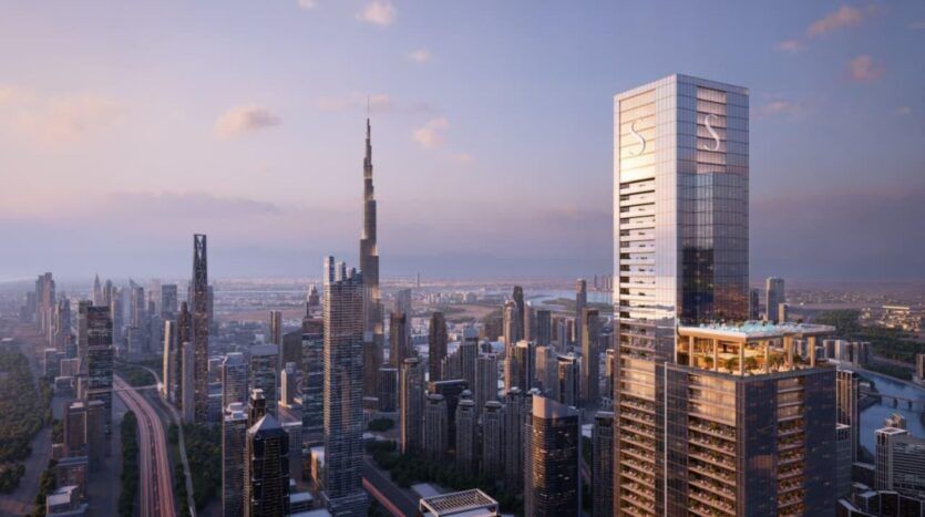 L'horizon d'une ville au coucher du soleil présente de nombreux gratte-ciel modernes. Le plus haut bâtiment, le Burj Khalifa, se dresse parmi d'autres gratte-ciel et des SkyParks nichés au sommet des toits. Le ciel brille d'une lueur douce et chaude et quelques nuages passent à la dérive.