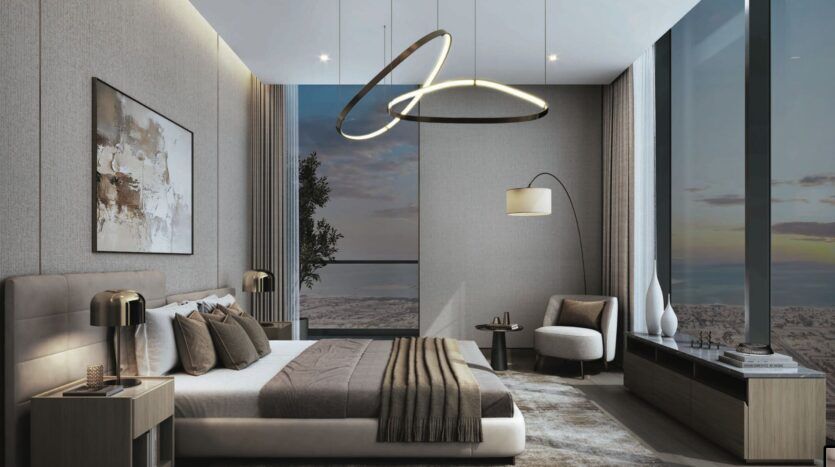 Chambre à coucher moderne avec de grandes fenêtres allant du sol au plafond, un lit avec une literie marron et beige, des lampes suspendues élégantes, une chaise longue avec un lampadaire, des œuvres d'art murales abstraites et une vue imprenable sur le coucher de soleil de la ville de SkyParks à l'extérieur.
