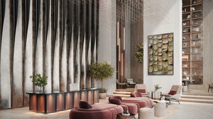 Le hall d'entrée moderne de l'hôtel Résidence Sunset Bay Grand par Imtiaz à Dubai Islands présente de hauts plafonds, des panneaux muraux métalliques ondulés, des sièges rouges en peluche, des arbres en pot, une grande peinture abstraite et une haute étagère présentant des objets décoratifs.