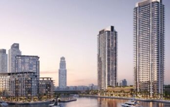 Des tours modernes et des appartements en bord de mer entourent le port de plaisance de Creek Bay, avec des yachts, des palmiers et une voie d'eau calme, sous un ciel doux en début de soirée.