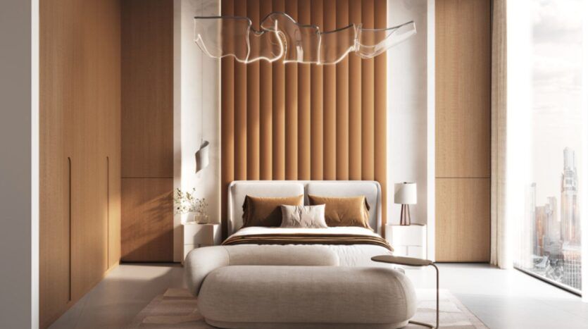 Une chambre à coucher Skyflame moderne avec un mur d'accent rembourré, un lit blanc avec une literie marron et blanche, un banc incurvé, des tables de chevet minimalistes, un plafonnier sculptural et de grandes fenêtres avec vue sur la ville.