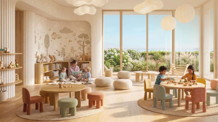 Une salle de classe Greenz by Danube, lumineuse et aérée, avec de grandes fenêtres, des meubles ronds et doux, et un décor pastel. Deux enfants jouent à des tables tandis qu'un adulte fait la lecture à trois enfants assis sur des coussins. Des plantes et des œuvres d'art murales créent une atmosphère chaleureuse et accueillante.