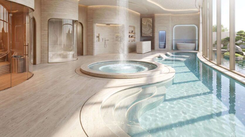 Le luxueux spa intérieur de Greenz by Danube comprend un jacuzzi circulaire avec une fontaine centrale, une piscine incurvée, un sauna, un espace douche, de grandes fenêtres et un décor minimaliste beige. La lumière naturelle remplit cet espace serein.