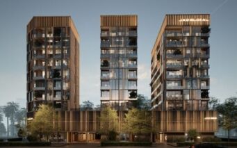 Trois bâtiments modernes de plusieurs étages avec des façades en verre et des lignes architecturales verticales - identifiés comme JAD288 - sont entourés d'arbres et d'aménagements paysagers, avec des enseignes "JAP GLOBAL" illuminées sur deux tours à la tombée de la nuit.