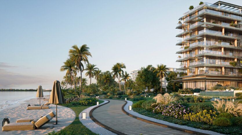 Une promenade en bois serpente à travers des jardins paysagers à côté des résidences modernes Cheval, avec des chaises longues et des parasols sur une plage de sable sous les palmiers au coucher du soleil.
