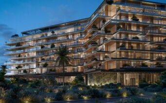 Un immeuble d'appartements de luxe moderne de plusieurs étages, les Résidences Cheval, est illuminé au crépuscule, avec de grandes baies vitrées, des balcons spacieux et des jardins paysagers luxuriants au premier plan. Des palmiers et des éclairages décoratifs renforcent l'ambiance élégante.