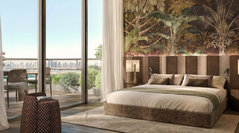 Chambre luxueuse des résidences Cheval avec un grand lit, un mur d'accent tropical, des fenêtres allant du sol au plafond et un balcon donnant sur l'horizon de la ville. La lumière du soleil envahit la pièce, mettant en valeur l'élégance du décor et la verdure à l'extérieur.