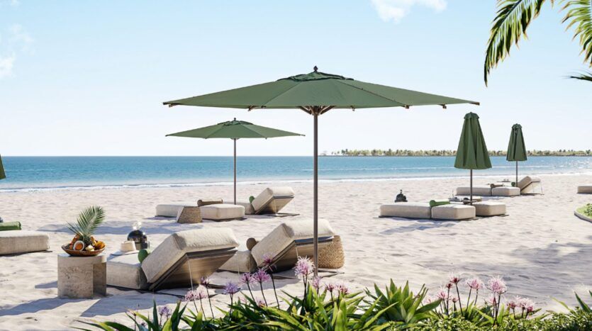 Scène de plage ensoleillée aux Résidences Cheval avec des chaises longues et des parasols verts sur le sable blanc, face à un océan bleu et calme. Des plantes et des fleurs tropicales occupent le premier plan, tandis qu'un plateau de fruits et de boissons est posé sur une petite table.