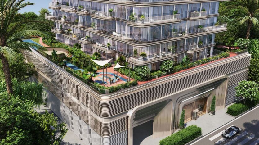 Bâtiment moderne de plusieurs étages, l'hôtel The Tides by Amis est doté de balcons en verre et de terrasses à la végétation luxuriante. Le toit offre une piscine, des espaces ombragés pour s'asseoir et des jardins. Des arbres entourent le bâtiment alors qu'une voiture passe devant l'entrée en contrebas.