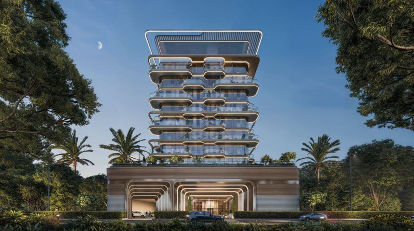 Bâtiment moderne de plusieurs étages avec des balcons incurvés et de grandes baies vitrées, The Tides by Amis est entouré de palmiers et de verdure, avec quelques voitures circulant sur la route devant et un croissant de lune dans le ciel.