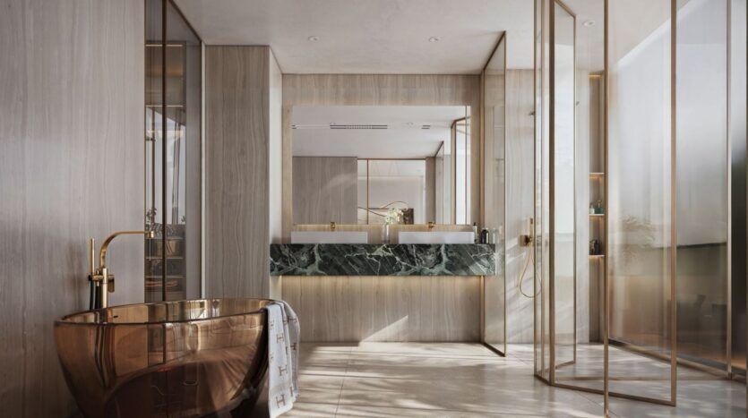 Une salle de bains moderne avec une baignoire autoportante en bronze de The Tides by Amis, deux lavabos avec des comptoirs en marbre vert foncé, de grands miroirs, une douche en verre et des panneaux en bois clair allant du sol au plafond, le tout baigné de lumière naturelle grâce à de hautes fenêtres.