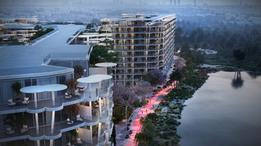 Des gratte-ciel modernes aux balcons incurvés surplombent un front de mer, entouré d'arbres et éclairé par des lampadaires au crépuscule, près des jardins de Sakura, avec une ligne d'horizon de la ville visible dans le lointain brumeux.