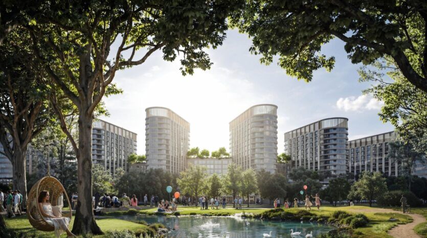 The Woods by Sobha est un complexe résidentiel moderne composé de grands immeubles entourant un parc luxuriant, où les arbres, un étang avec des cygnes et des promeneurs créent une scène animée sous un ciel clair. Une femme se détend dans un fauteuil suspendu au milieu de cette beauté.