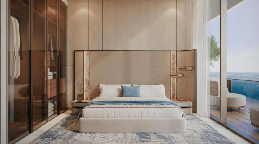 Chambre moderne dotée d'un grand lit, d'une parure de lit bleue et blanche, de murs lambrissés, d'une armoire vitrée et de baies vitrées s'ouvrant sur un balcon offrant une vue imprenable sur la mer depuis la « Vue Dorée ».