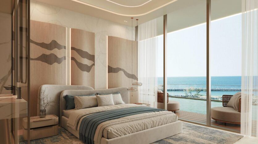 Chambre moderne dotée d'un grand lit, de tons neutres, d'une décoration murale élégante, de baies vitrées et d'une vue sur l'océan à la résidence Vue Dorée. Un balcon aménagé d'un coin salon invite à la détente, tandis que la lumière naturelle inonde cet espace à la fois chaleureux et raffiné.