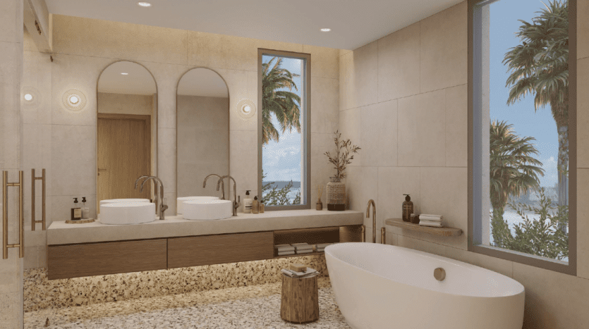 A luxurious bathroom featuring a freestanding bathtub, two sinks, wooden cabinets and a large window with tropical views. The décor features modern fixtures and natural light, perfect for an apartment