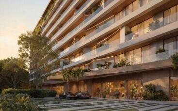 Lunaya Terraces est un immeuble d'appartements moderne de plusieurs étages, doté de grands balcons, d'espaces verts abondants et de baies vitrées. Deux voitures de luxe sont garées devant, tandis que des coins salon en plein air et un aménagement paysager luxuriant entourent le site.