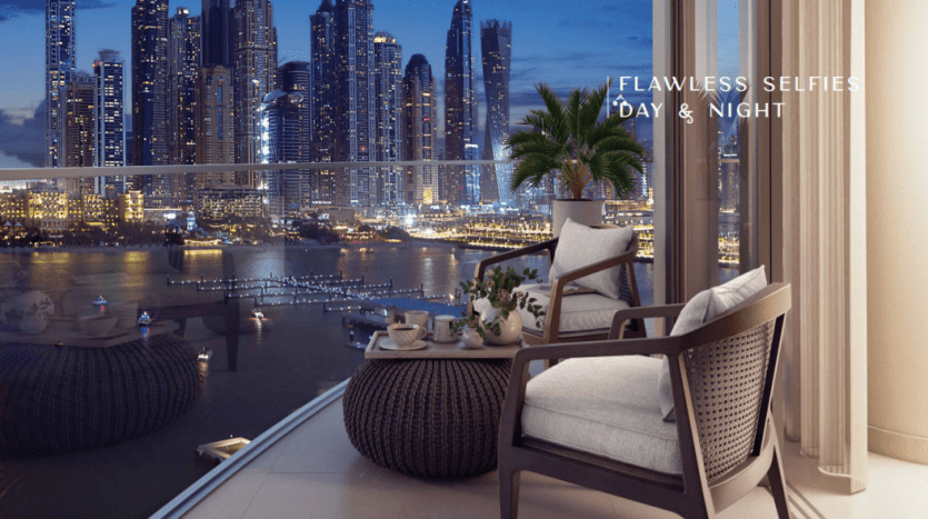 Balcon luxueux de la résidence Palace Beach surplombant les toits de la ville la nuit, comprenant des meubles de patio, une théière posée sur une table et des bâtiments éclairés de l'autre côté d'une rivière. La superposition de texte indique "défaut