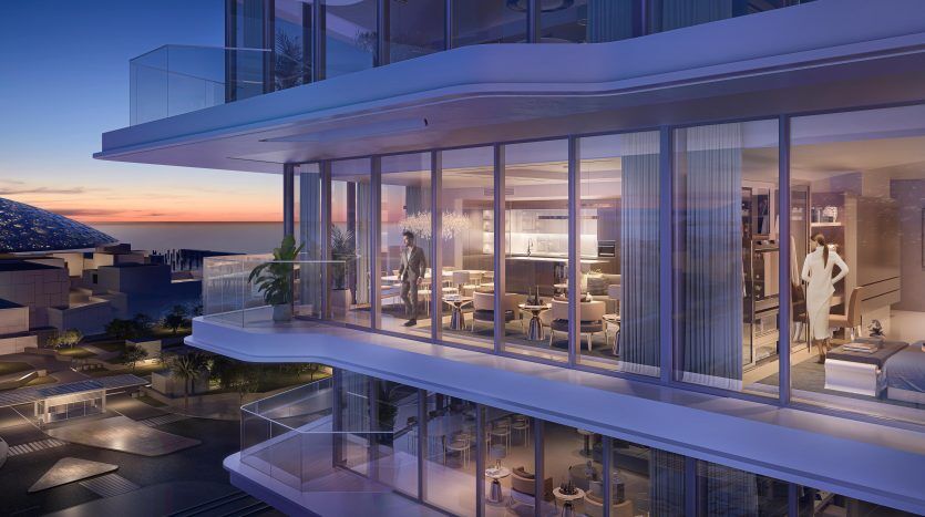 Une luxueuse façade d'appartement moderne au crépuscule avec de vastes murs de verre, révélant des espaces intérieurs élégants. Une femme se tient à l’intérieur, près du balcon, surplombant les toits de Dubaï.