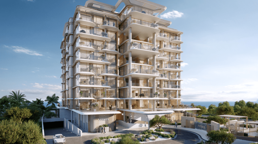 Un immeuble d'appartements moderne à plusieurs étages avec de grands balcons et un design épuré, rappelant les luxueux complexes de Palm Jumeirah. Entouré de verdure et sur fond de ciel bleu clair, l'entrée comporte le mot « VAANIA », incarnant l'élégance et la vitalité.
