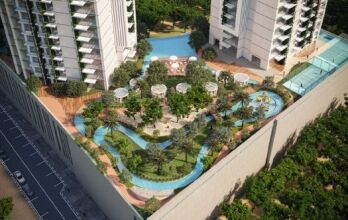 Aerial view of a luxury residential complex in Dubai featuring curved pools, lush greenery, relaxation areas and modern high-rise buildings on a sunny day.
