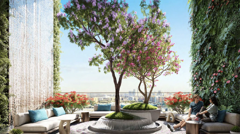 A rooftop garden in Dubai with lush greenery and colorful flowers. Two people relax on a sofa enjoying the view. Water features and city rooftops in the background.