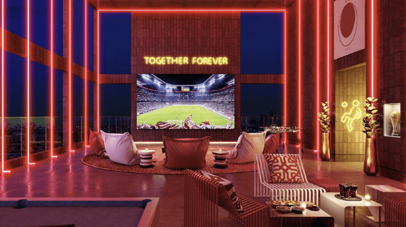 A sumptuous home theater in a Dubai apartment with bright blue and red neon lights, plush seating and a big screen displaying a soccer match, all adorned with comfortable, elegant decor.