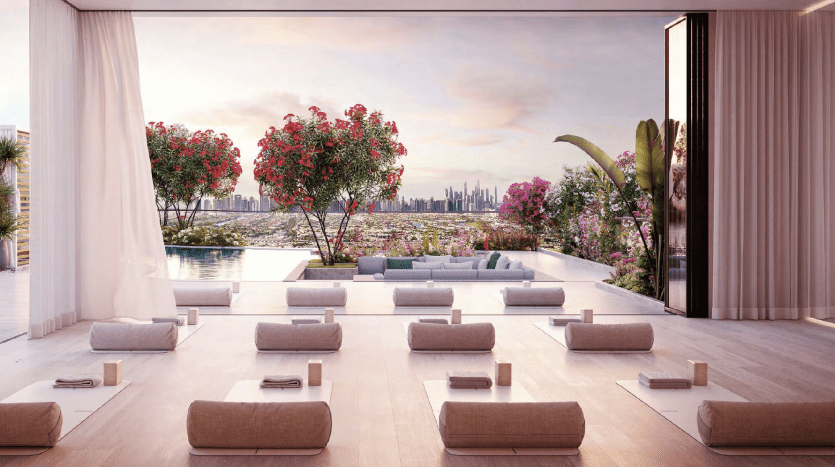 Elegant outdoor seating area with modern beige sofas and cushions, overlooking city rooftops beyond an infinity pool, framed by bright red flowering trees under a soft pink sky in a Dubai villa.