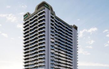 Un grand immeuble moderne, Reef 996, avec de nombreux balcons et baies vitrées, se dresse sur un ciel bleu parsemé de nuages. La structure présente des angles incurvés et des panneaux de signalisation sur le toit.