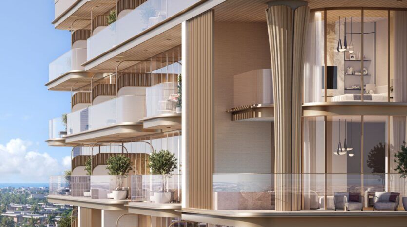 Le 113 Residences by Iman est un immeuble d'appartements de luxe moderne doté de vastes balcons en verre, de hautes fenêtres, d'un éclairage élégant et de plantes d'extérieur. Des tons neutres et chauds dominent la façade, avec des vues sur l'océan et la ville sous un ciel bleu limpide.