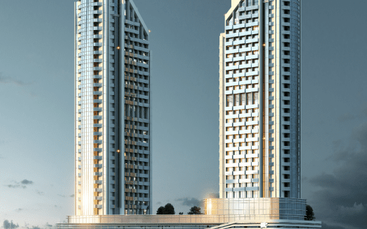 Dos grandes rascacielos modernos con ventanas iluminadas se elevan sobre una gran estructura de base contra un cielo crepuscular en Dubai.