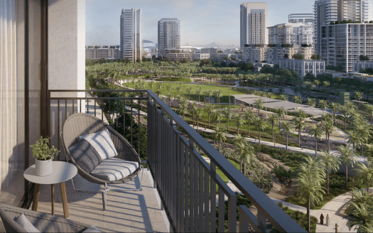 Vista desde un balcón alto con vistas a un frondoso parque urbano de Dubai, con senderos para pasear rodeados de modernos rascacielos, que incluye una única silla y una pequeña mesa con una planta.