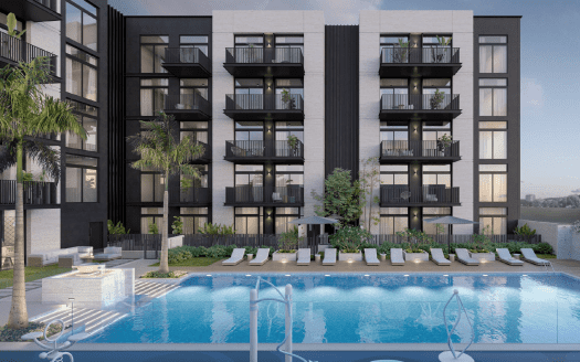 Moderno edificio de apartamentos con balcones que dan a una piscina rodeada de palmeras, tumbonas y fuentes, con el telón de fondo del paseo marítimo de Dubai.