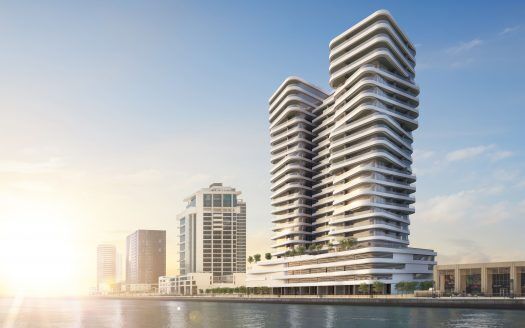 Modernos edificios frente al mar de arquitectura curvilínea bajo un cielo despejado de Dubai, que refleja el amanecer en las tranquilas aguas.